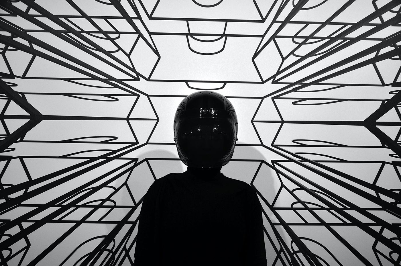 La silhouette di una persona davanti a un motivo geometrico di linee in bianco e nero